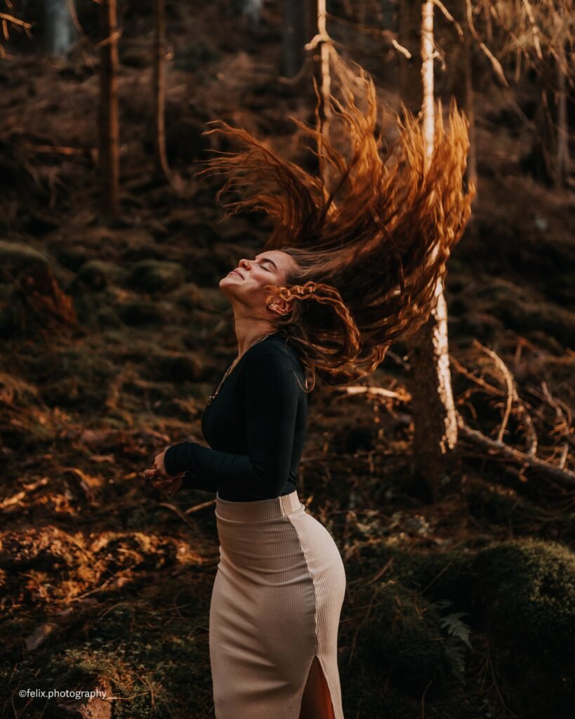 Frau mit wehenden Haaren vor herbstlichem Wald
