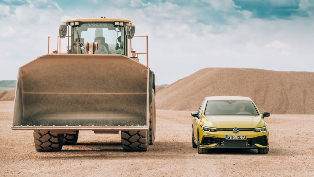 Gelber VW Golf neben einem großen Radlader