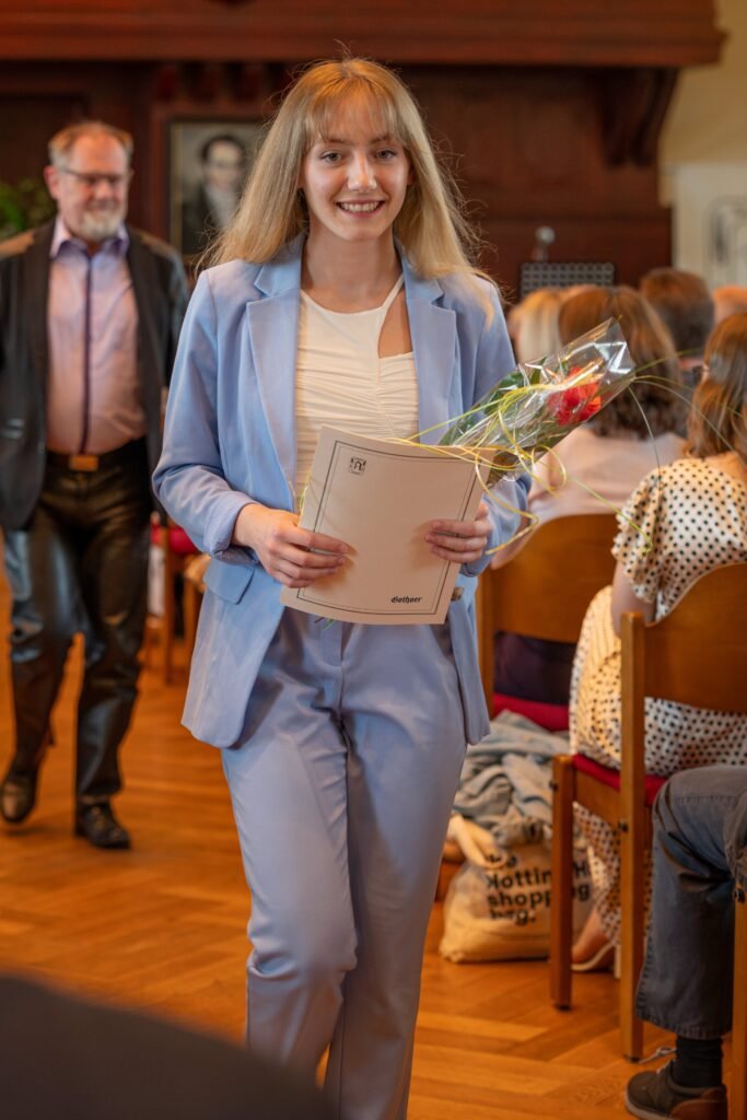 Teilnehmerin mit Blumen und Unterlagen im Veranstaltungssaal