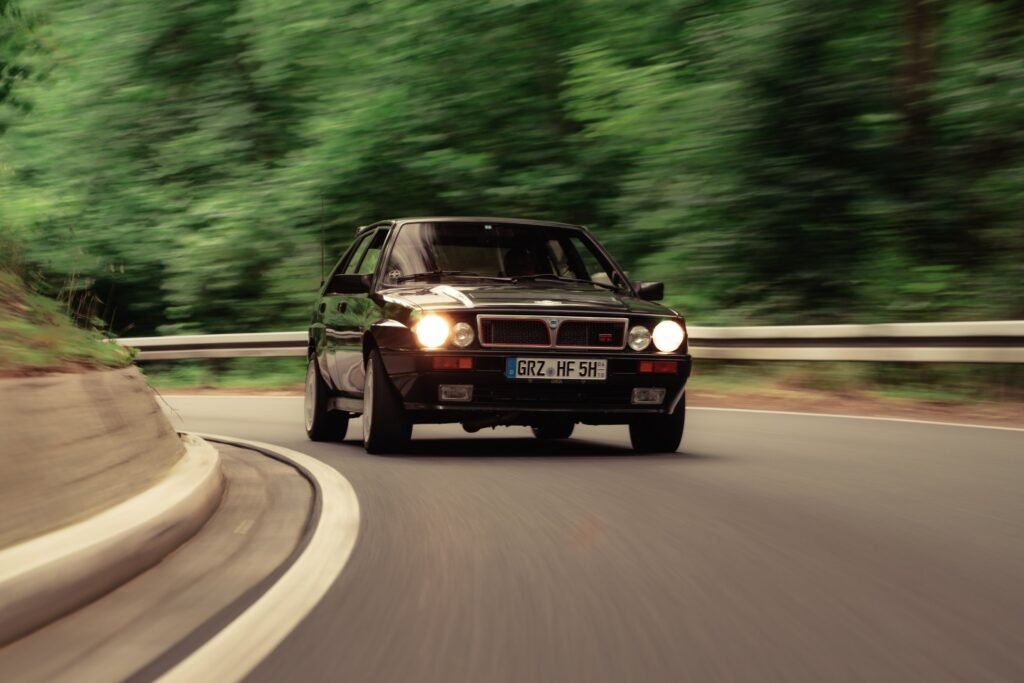 Schwarzer BMW in einer Straßenkurve vor grünem Wald