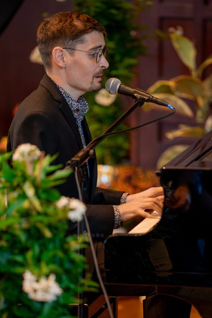 Musiker singt am Mikrofon und spielt Klavier