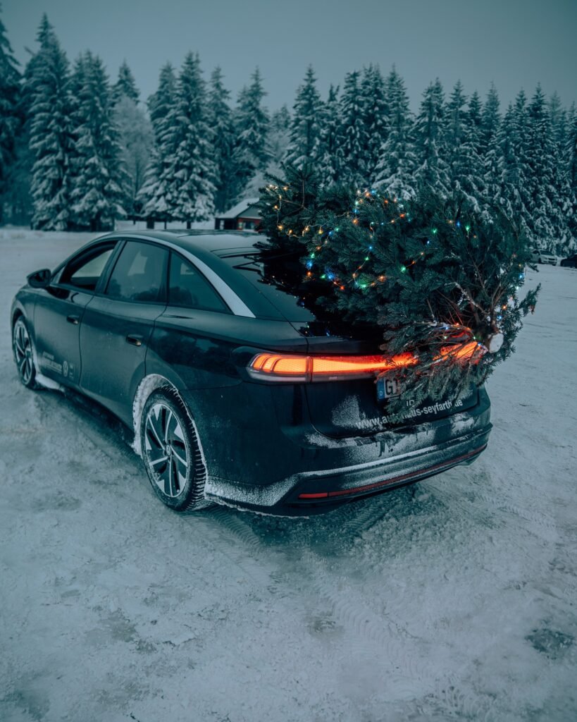 Dunkler SUV mit Weihnachtsbaum im verschneiten Wald