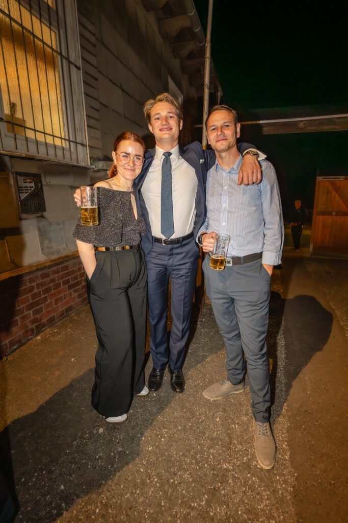 Drei Gäste beim Gruppenportrait am Abend im Freien