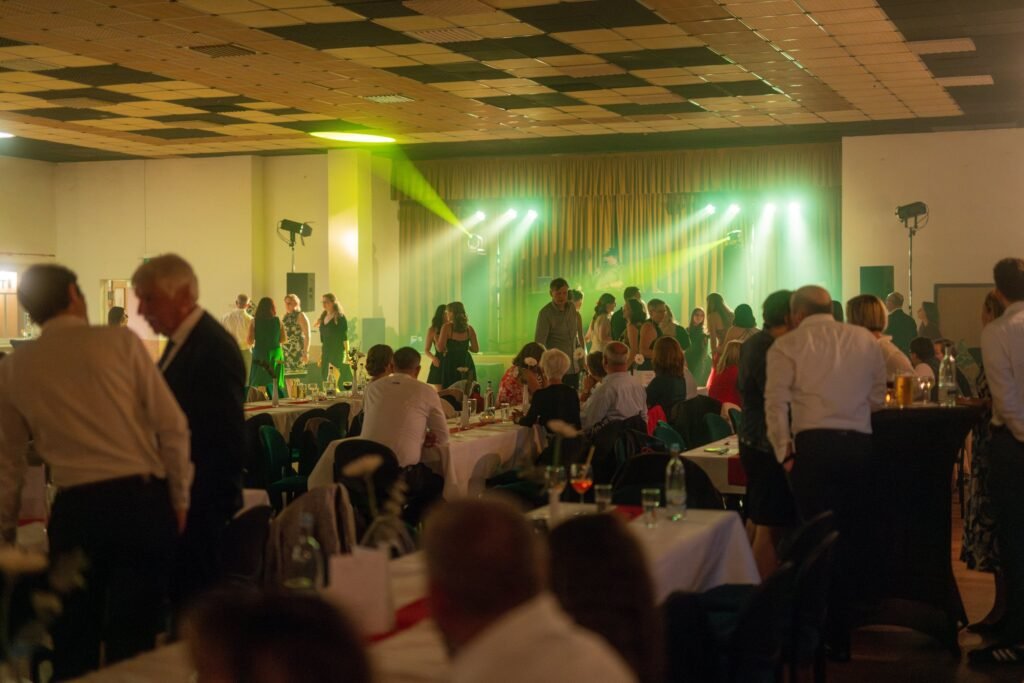 Festsaal mit Gästen und grüner Bühnenbeleuchtung