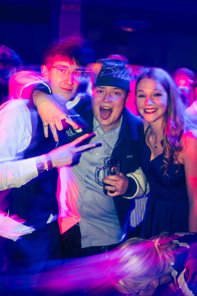 Drei Gäste posieren gemeinsam im farbigen Partylicht