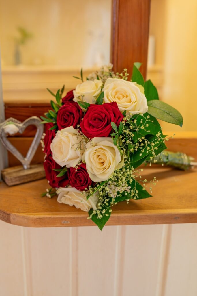 Brautstrauß mit roten und weißen Rosen auf einem Stuhl
