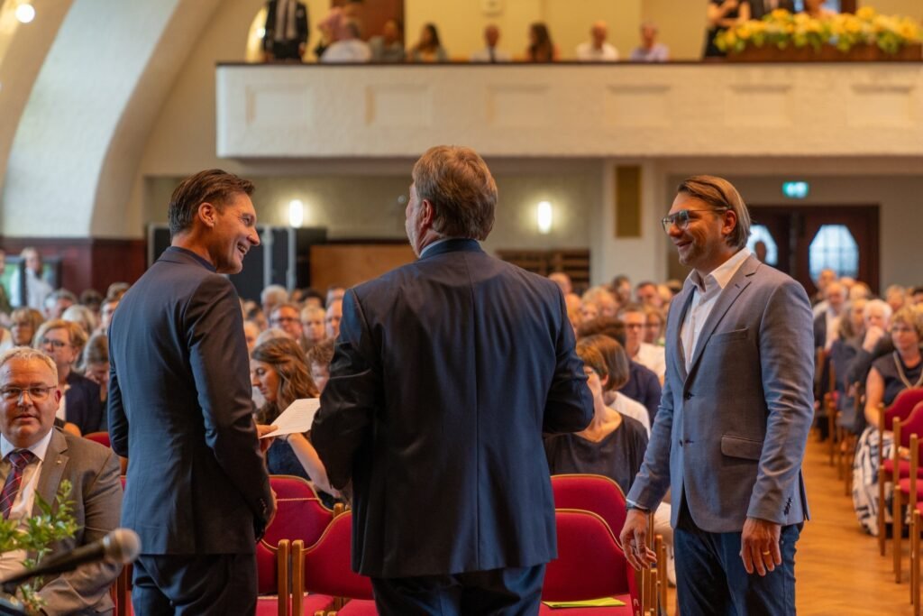 Drei Männer im Gespräch vor dem Publikum im Saal