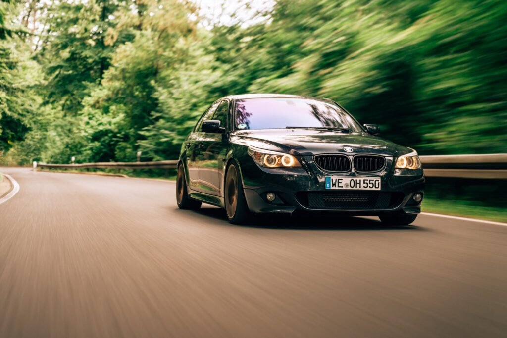 Schwarzes BMW Cabrio während einer Fahrt auf einer bewaldeten Straße