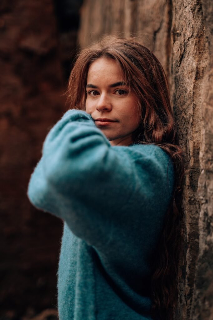Portrait einer Frau in blaugrünem Pullover an einem Baum
