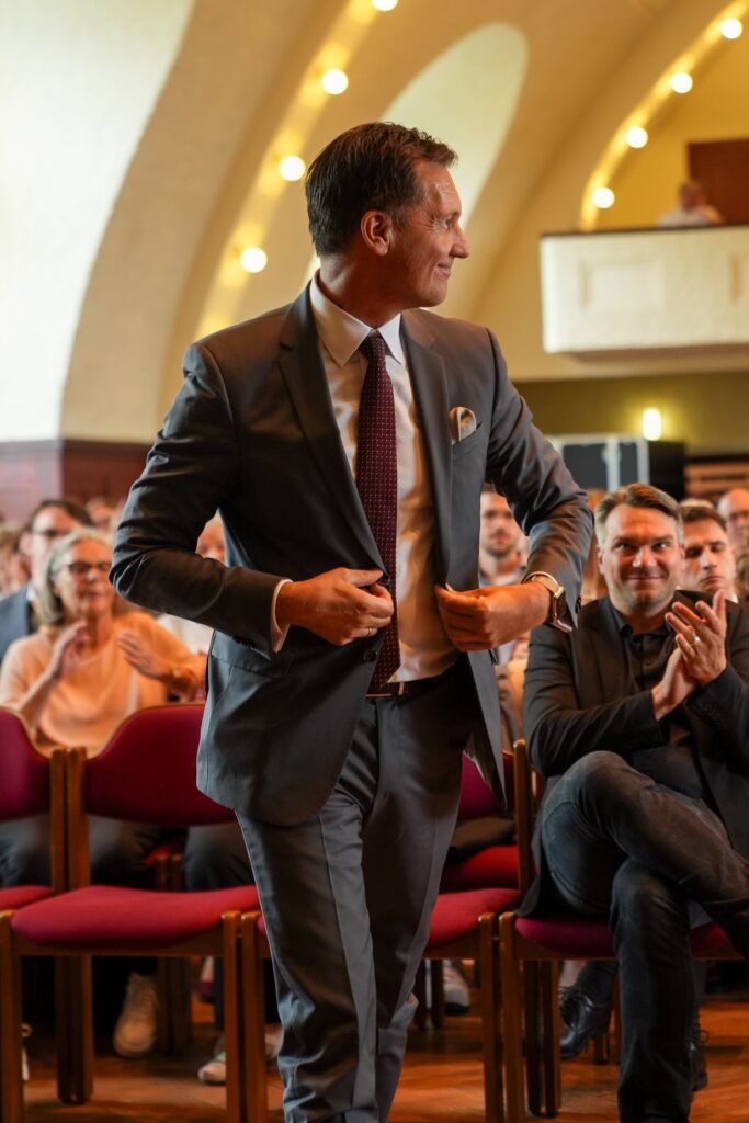 Gast mit Getränken vor dem Publikum im Veranstaltungssaal