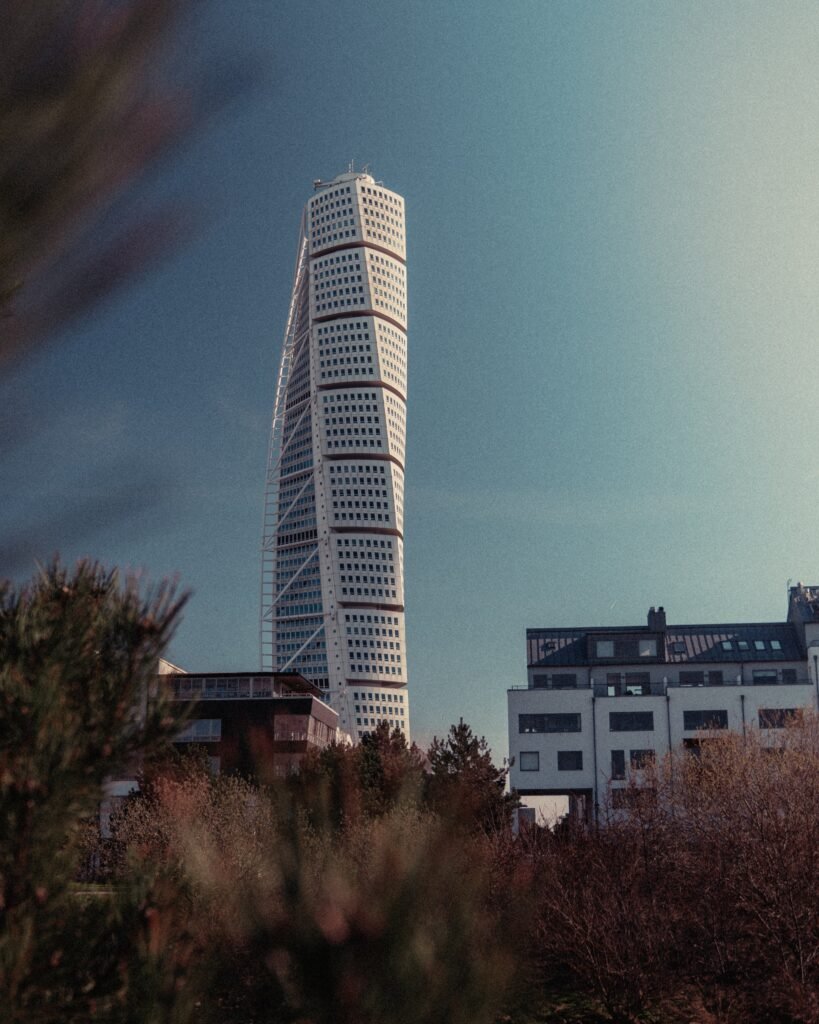 Gedrehtes Hochhaus über niedrigeren Stadtgebäuden