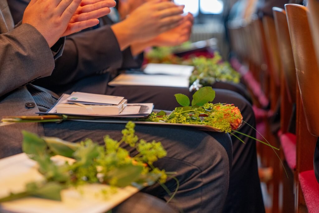 Blumen und Unterlagen auf den Knien von Veranstaltungsgästen