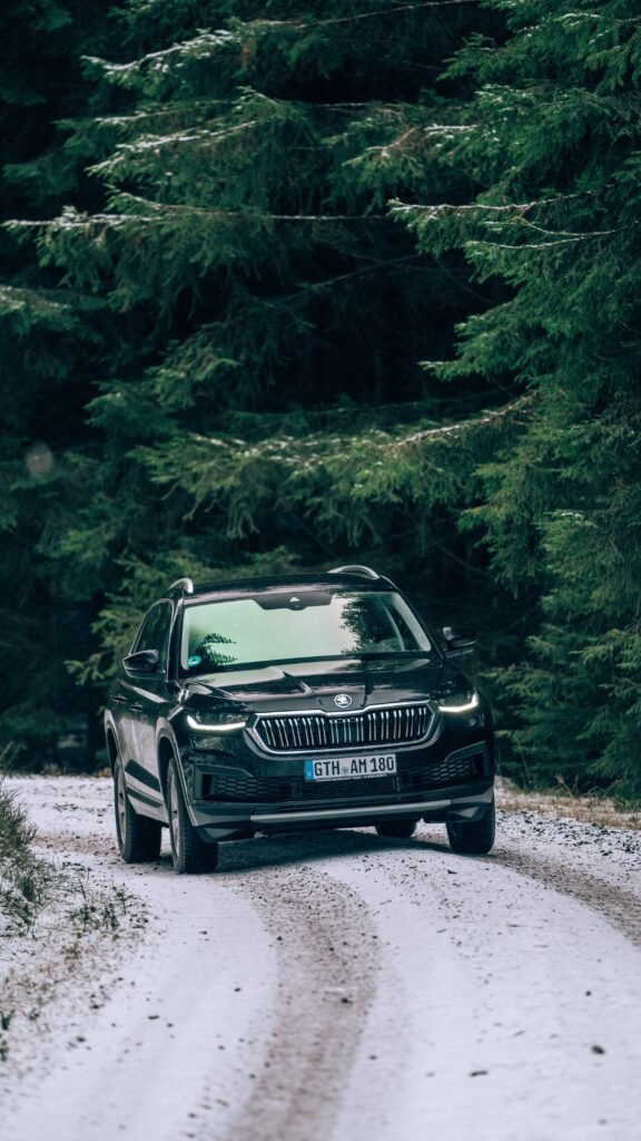 Dunkler SUV auf einem verschneiten Waldweg