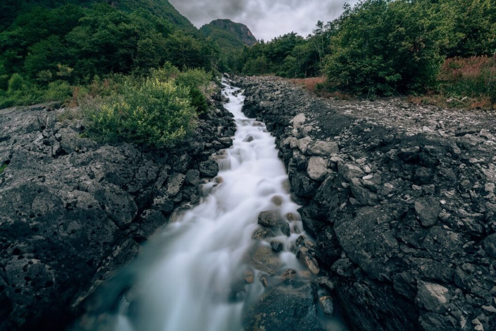 Fluss zwischen Felsen und grünen Berghängen